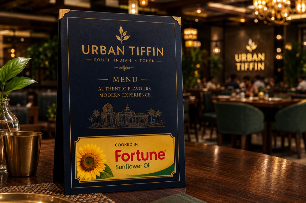 Concept mock-up: a navy and gold menu card standing on a restaurant table, with a cooking-oil brand panel across the bottom.